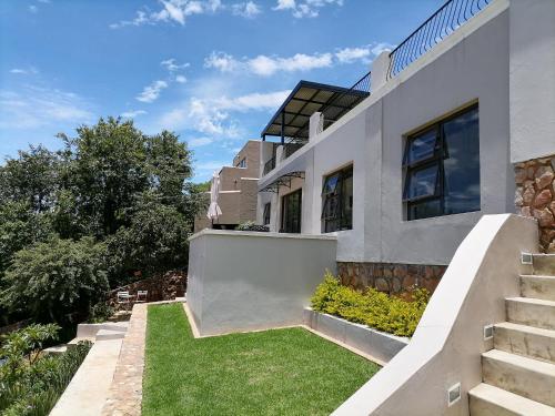 a white house with stairs and grass at CityView, a stunning modern apartment in Johannesburg