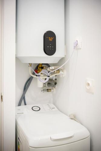 a machine with a clock above a washing machine at Superbe appartement plein centre, calme, Netflix in Mirepoix