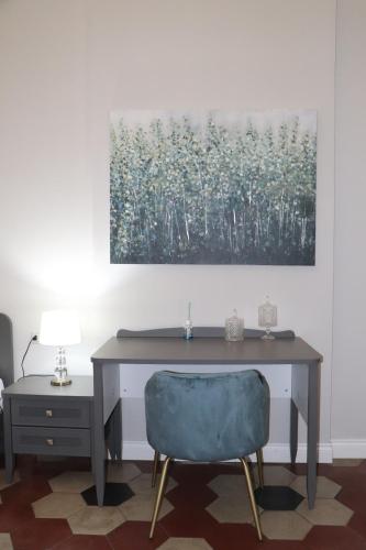 a desk with a chair and a painting on the wall at DOMUS IOLE appartamento nel centro storico in Catania