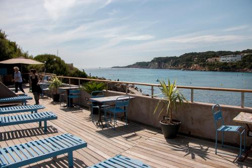 a deck with tables and chairs next to the water at O Petit Monde in Sanary-sur-Mer
