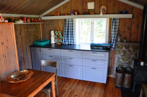 eine Küche mit einer Theke, einem Tisch und einem Fenster in der Unterkunft Hytte fra 1721 uten internett, strøm, vann - men med rødmalt utedo in Ljørdal