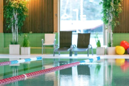 a pool with two chairs and a swimming pool at First Camp Enåbadet - Rättvik in Rättvik
