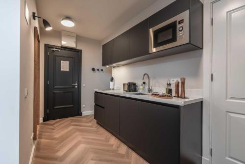 a kitchen with black cabinets and a black door at limehome Den Haag Keizerstraat in Scheveningen