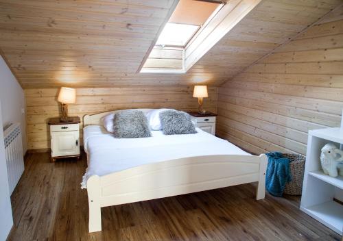 een slaapkamer met een wit bed in een houten muur bij Między OWCAMI in Sromowce Wyżne