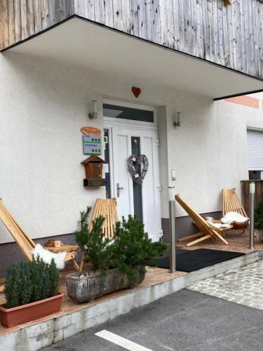 eine Eingangstür eines Gebäudes mit Stühlen und einer Veranda in der Unterkunft Aparthotel Pr' Jakapč' in Mojstrana