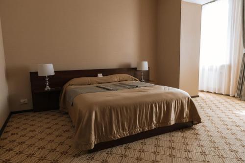 a bedroom with a bed in a room with a window at Medeu in Kostanay