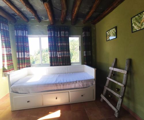 Ce lit se trouve dans un dortoir doté d'une fenêtre et d'une échelle. dans l'établissement Acogedor alojamiento Trevelez, à Trevélez