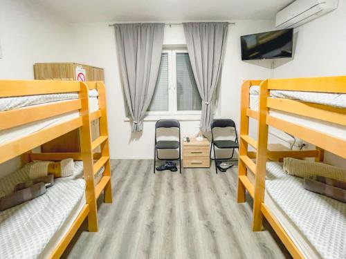 a room with three bunk beds and a tv at Katarina Rooms in Novi Kneževac