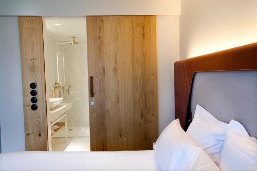 a bedroom with a bed with a wooden door and a bathroom at Hotel Les Haras in Strasbourg
