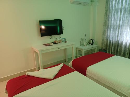 a hotel room with two beds and a tv at Beach Grand & Spa Premium in Hulhumale