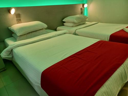 two beds with red and white sheets in a room at Beach Grand & Spa Premium in Hulhumale
