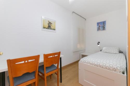 ein Schlafzimmer mit einem Bett, einem Schreibtisch und zwei Stühlen in der Unterkunft Cadillac 3 hab AC BCN cerca Airport Parking Tram in Cornellà de Llobregat