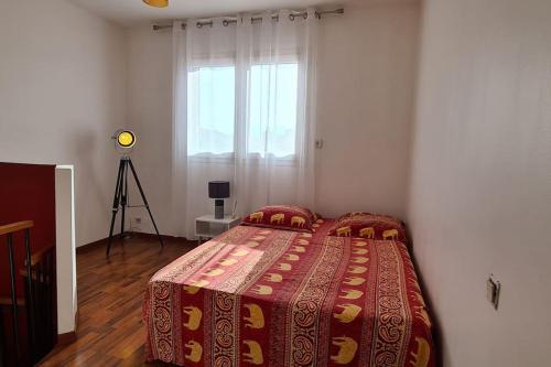 um quarto com uma cama com um cobertor e uma janela em Proche mer appartement avec jardin,place parking. em Elne