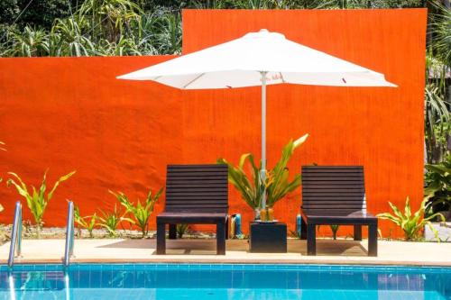 zwei Stühle und ein Sonnenschirm neben einem Pool in der Unterkunft Natai House in Natai Beach