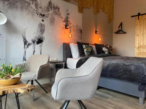 a bedroom with a bed with two chairs and a deer mural at Landelijk overnachten bij Vechtdals Mooiste in Giethmen