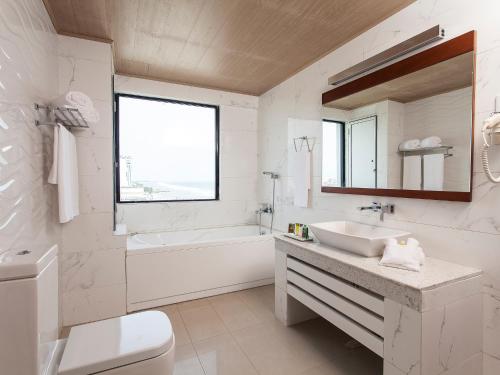 a bathroom with a sink and a tub and a toilet at The Ocean Colombo in Colombo