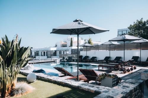 a swimming pool with chairs and umbrellas at Seascape Luxury Residences in Agia Pelagia