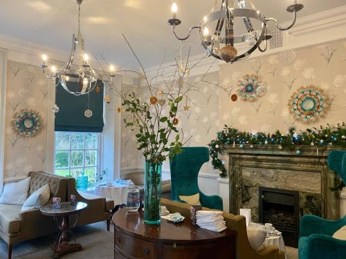 a living room with a fireplace and a chandelier at Barnett Hill Hotel in Guildford