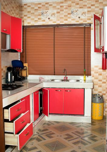 a kitchen with red cabinets and a sink at Yussals Luxury Apartment in Kokrobite