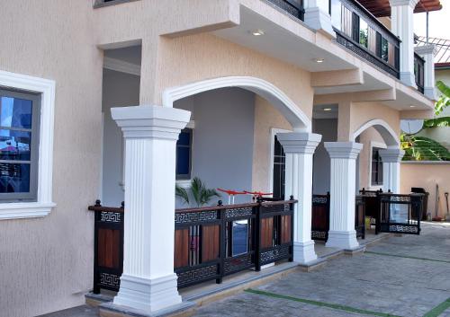 a house with white columns and a balcony at Yussals Luxury Apartment in Kokrobite