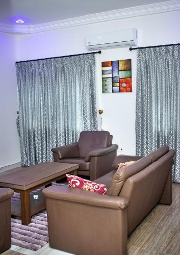 a living room with a couch and chairs and a table at Yussals Luxury Apartment in Kokrobite