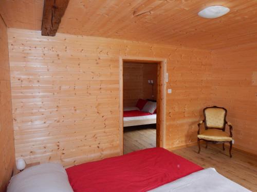 um quarto com uma cama e uma cadeira num quarto em Au Cheval Blanc em Asuel