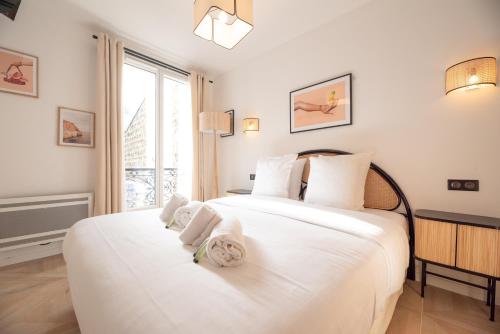 um quarto com uma grande cama branca com toalhas em MBM - Michelis em Neuilly-sur-Seine