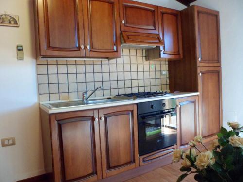 uma cozinha com armários de madeira, um lavatório e um fogão em Studio with furnished terrace and wifi at Pescia Romana 3 km away from the beach em Pescia Romana