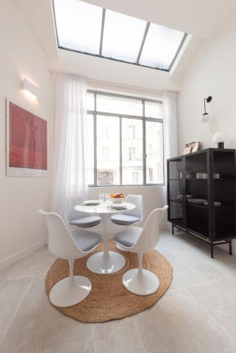 une salle à manger avec une table et des chaises blanches dans l'établissement Cerisaie, à Paris