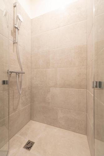 une salle de bain avec une douche avec une porte vitrée dans l'établissement Cerisaie, à Paris