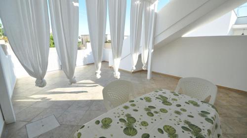 a table and chairs in a room with white curtains at Villetta Bianca by Salento Affitti in Torre San Giovanni Ugento