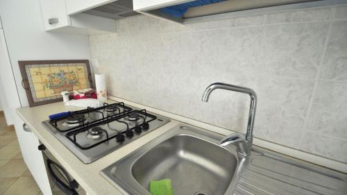 a kitchen with a stove and a sink at Villetta Bianca by Salento Affitti in Torre San Giovanni Ugento