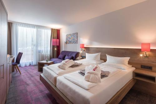 a hotel room with a large bed and a couch at Vivea Hotel Bad Bleiberg in Bad Bleiberg
