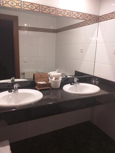 uma casa de banho com 2 lavatórios e um espelho grande em Hotel Giral em Biescas