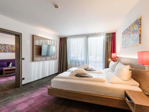 a hotel room with a large bed and a tv at Vivea Hotel Bad Bleiberg in Bad Bleiberg