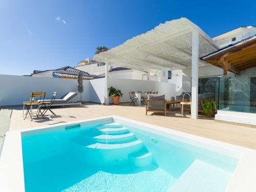 a blue swimming pool in front of a house at Pasitoblanco Porto Mare 45 Seaview Villa prívate heated pool in Pasito Blanco