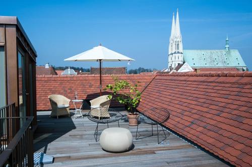 a patio with chairs and an umbrella on a roof at Emmerich Hotel Görlitz in Görlitz