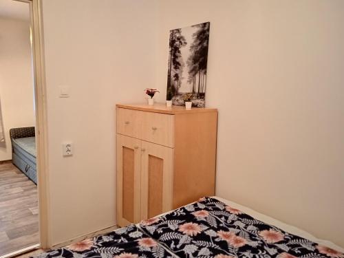 a bedroom with a bed and a dresser with flowers on it at Kispatak Erdei Ház in Verőce