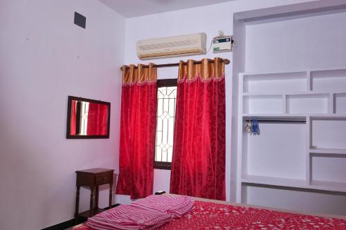 a bedroom with red curtains and a window at Villa Souhayl homestay in Pondicherry