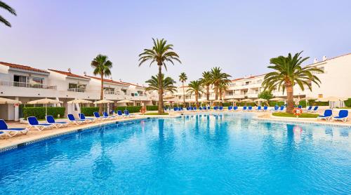 a large swimming pool with blue chairs and palm trees at Globales Los Delfines in Cala en Blanes