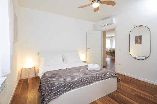 um quarto branco com uma cama e um espelho em La Casa di Riva em Riva del Garda