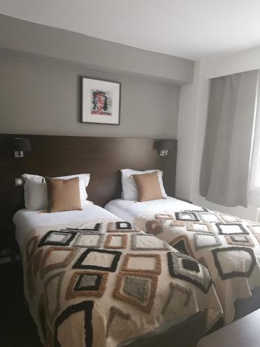 two beds sitting next to each other in a bedroom at The Originals Boutique, Hôtel d'Angleterre, Le Havre, centre, plage in Le Havre