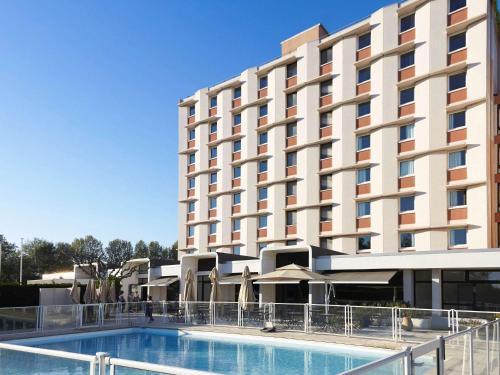 a hotel with a swimming pool in front of a building at ibis Styles Arles Palais des Congrès in Arles