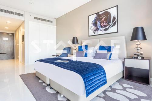 a bedroom with a large bed with a blue blanket at Staycae Holiday Homes - Artesia in Dubai