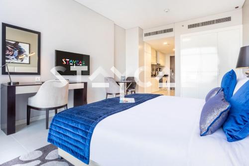 a bedroom with a bed with blue pillows and a desk at Staycae Holiday Homes - Artesia in Dubai