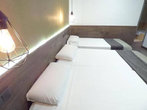 three beds in a room with white sheets and lights at Moderno in Barcelona