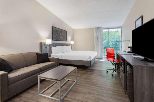 a hotel room with a bed and a couch at Ramada by Wyndham Hartford North - Bradley Airport in Windsor Locks