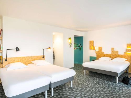 greet Hotel Rennes Pace في Pacé: سريرين في غرفة بجدران بيضاء