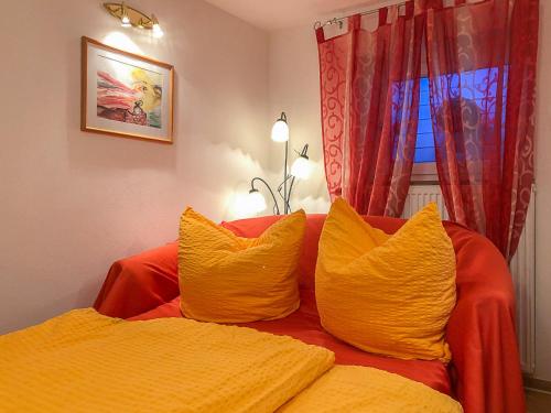 two yellow pillows on a red couch with a window at Neanderland-Apartment in Wülfrath