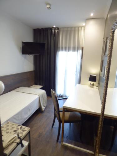 a hotel room with two beds and a desk and a mirror at Moderno in Barcelona